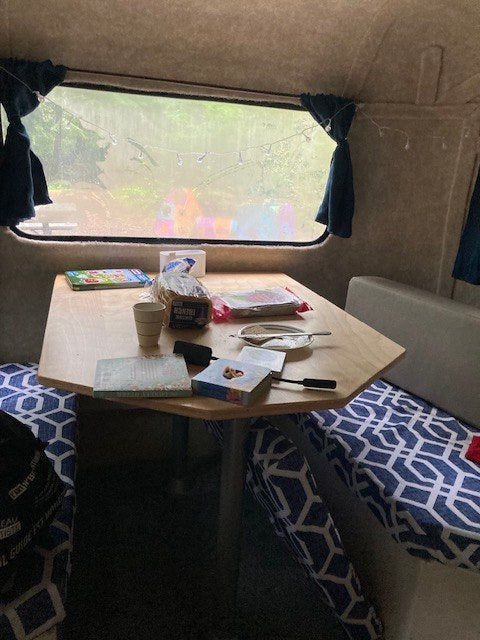 and dinette with blue cushions & curtains. Perfect for your next adventure.|Cozy camper interior for your next RV rental adventure. Features bench seating