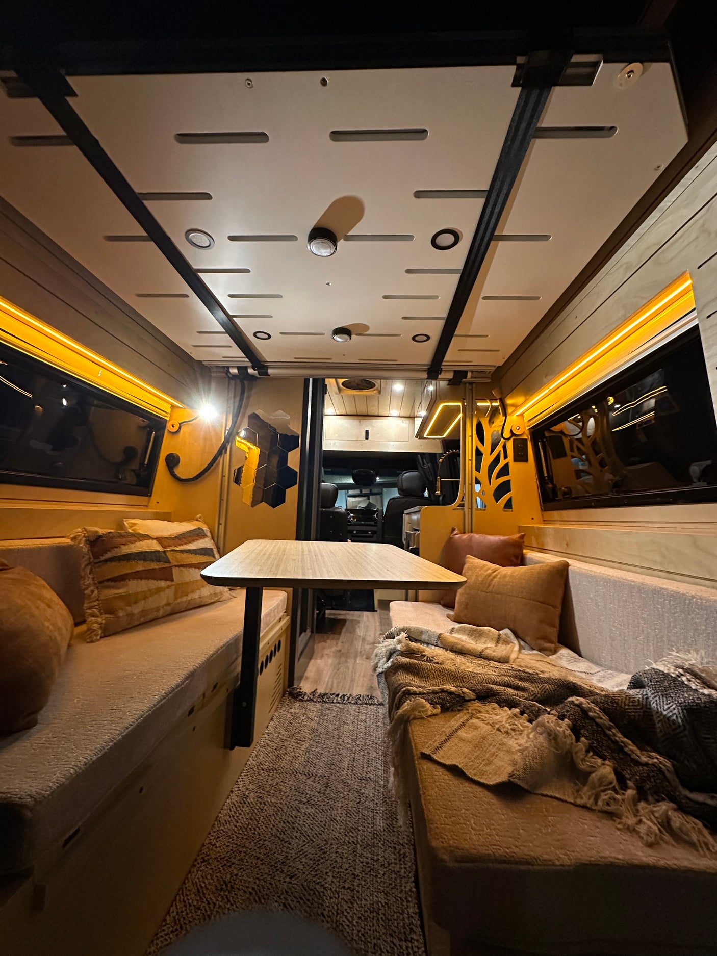 Cozy RV rental interior with comfortable lounge seating and dining table. Warm lighting creates an inviting ambiance.