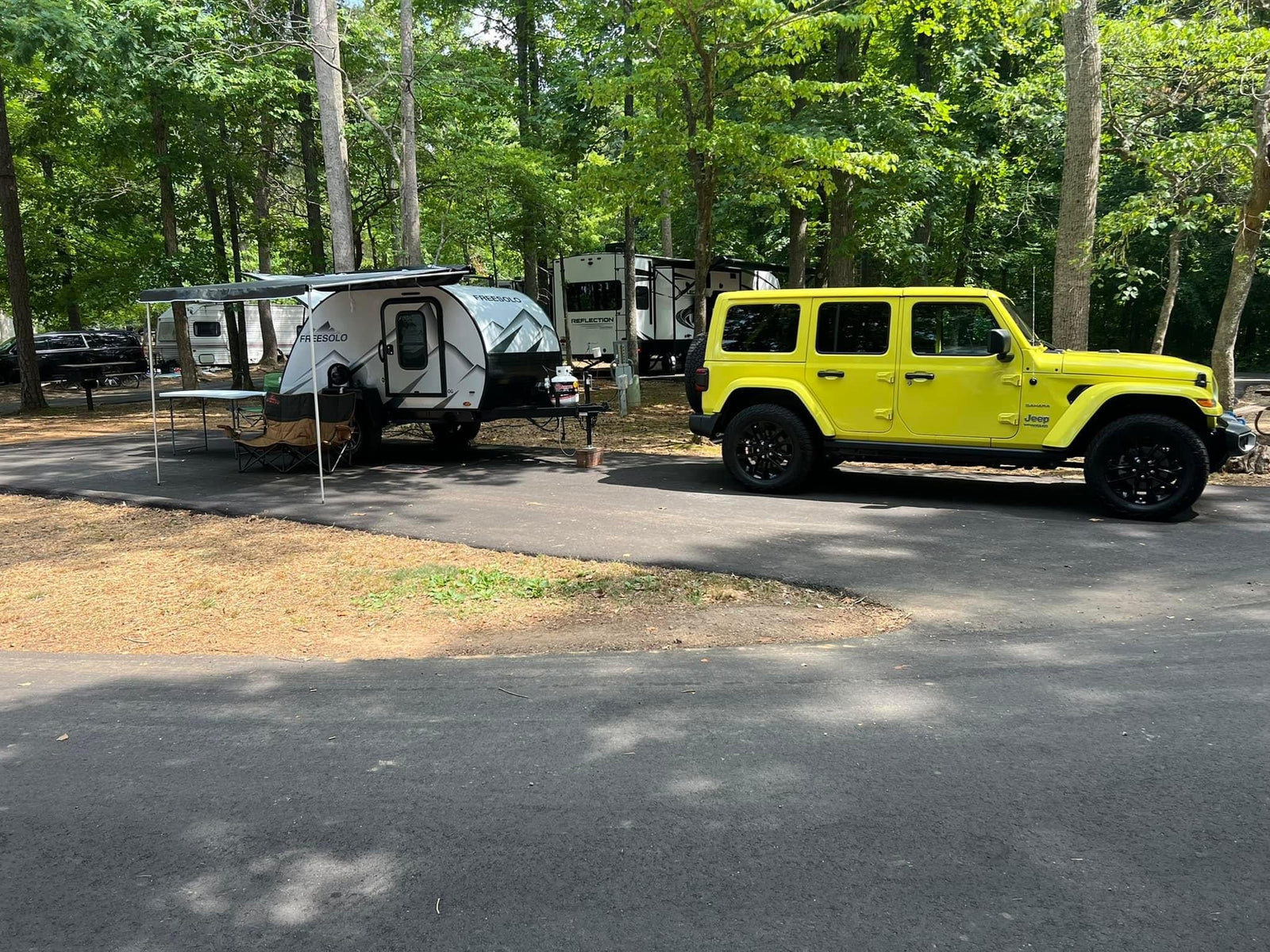Yellow Jeep & FREESOLO teardrop RV/trailer at a wooded campsite, showcasing a great option for an rv rental adventure.