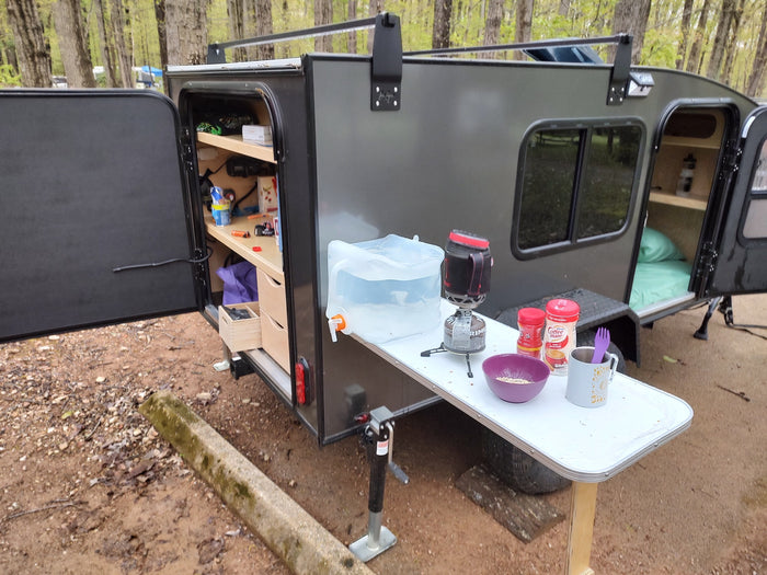 This RV rental teardrop trailer features a functional outdoor kitchen and comfy sleeping area, perfect for a cozy camping breakfast.