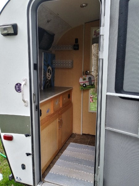 and a small kitchen for easy travel.|Inside a functional RV rental: cozy seating converts to a bed