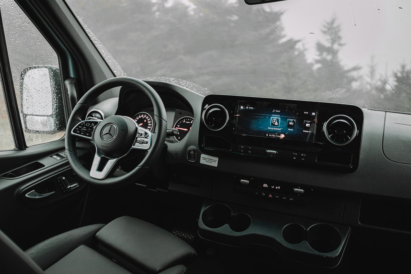 Inside a modern Mercedes-Benz van, ready for your next RV rental adventure on a rainy day. Shows the dashboard and infotainment.