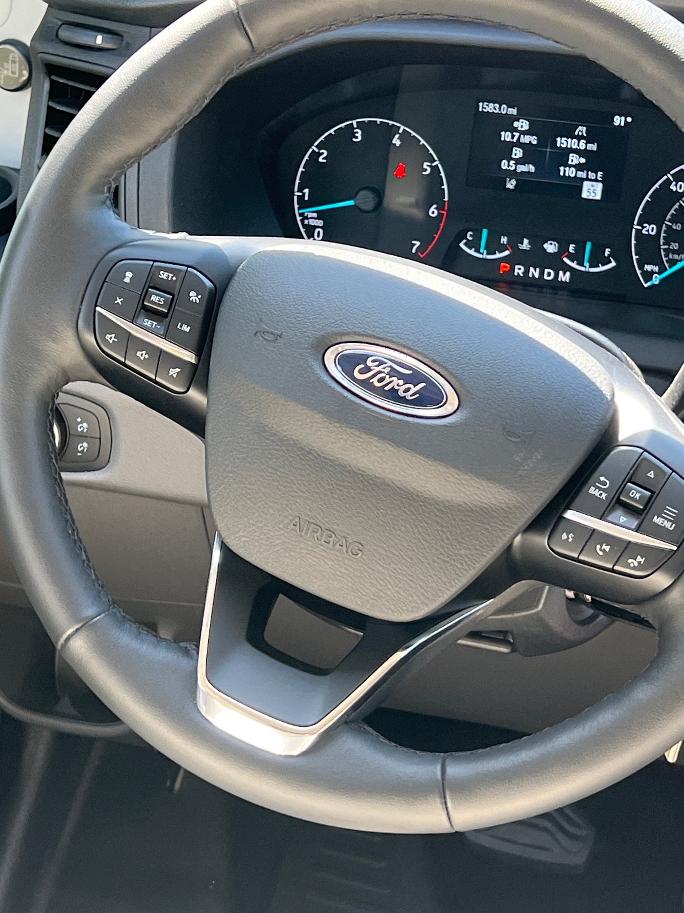 Inside a Ford RV rental: dashboard and steering wheel view. Digital display shows mileage, fuel, and vehicle controls.