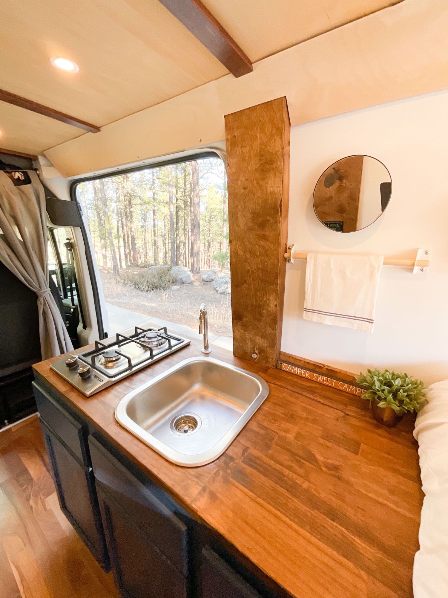 showing its cozy interior.|Inside a stylish RV rental: a compact kitchen with stove & sink