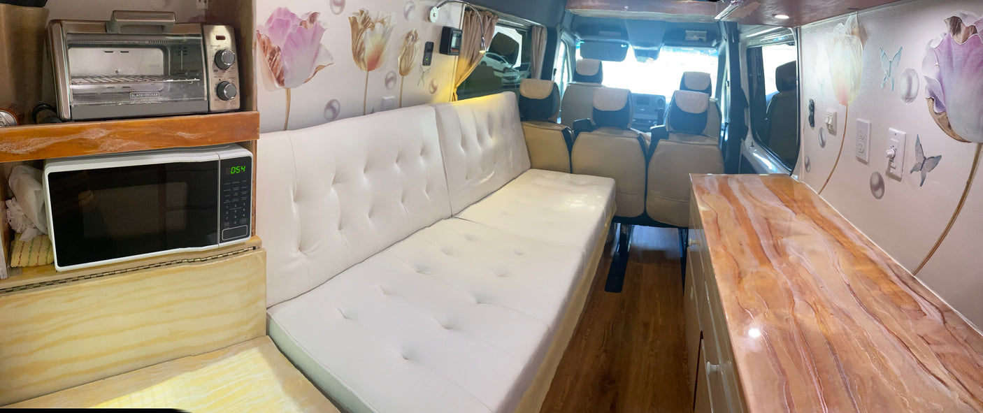 Spacious RV rental living area with white futon, microwave, toaster oven, and decorative counter. Ideal for travel!