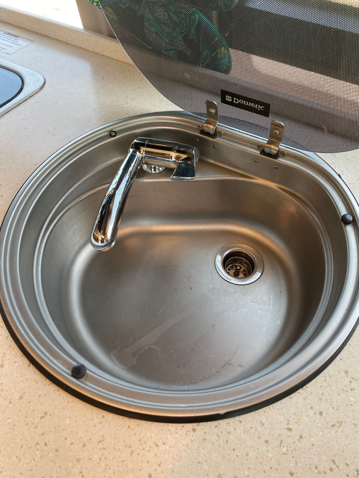 Stainless steel sink and faucet with an open Dometic glass lid, typical of an RV rental kitchen setup. — photo 7