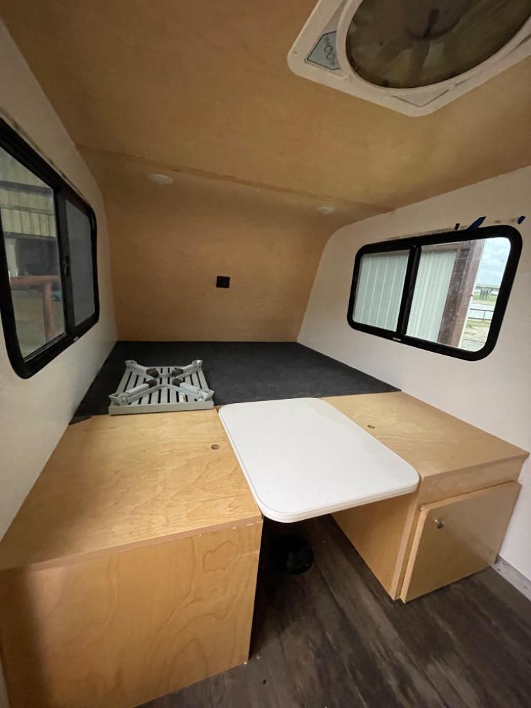 ready for your next rv rental journey.|Top view of an RV rental with a roof rack and a bold bear logo. Rustic Trail branding visible on this adventure trailer.|This RV rental interior features light wood cabinetry
