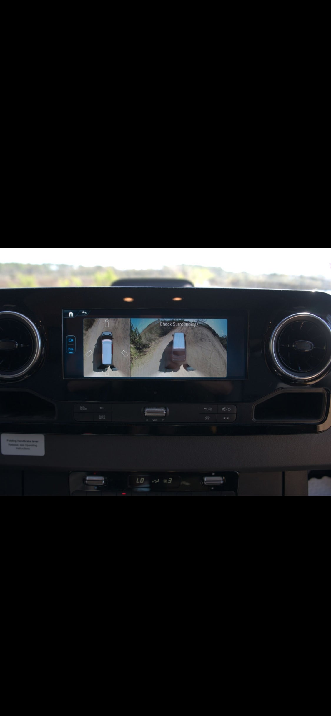RV rental dashboard: infotainment screen shows 360-degree camera view ("Check Surroundings") of the vehicle on a dirt road.
