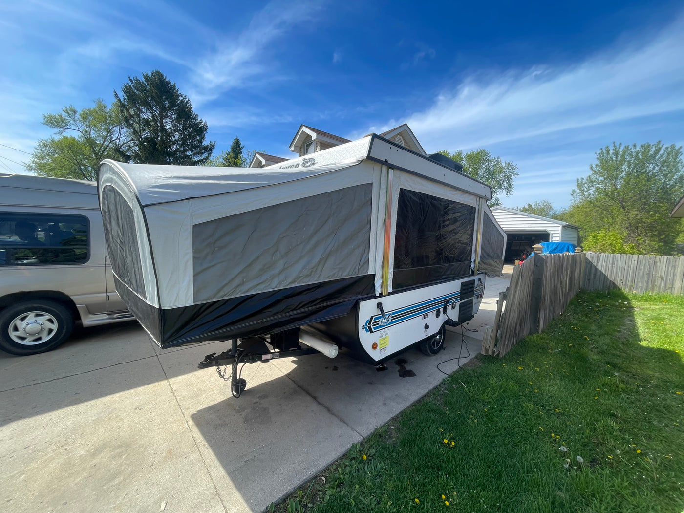 Extended pop-up RV, great for rv rental, parked on a driveway with a gray van. Sunny day, trees & fence visible. — photo 4
