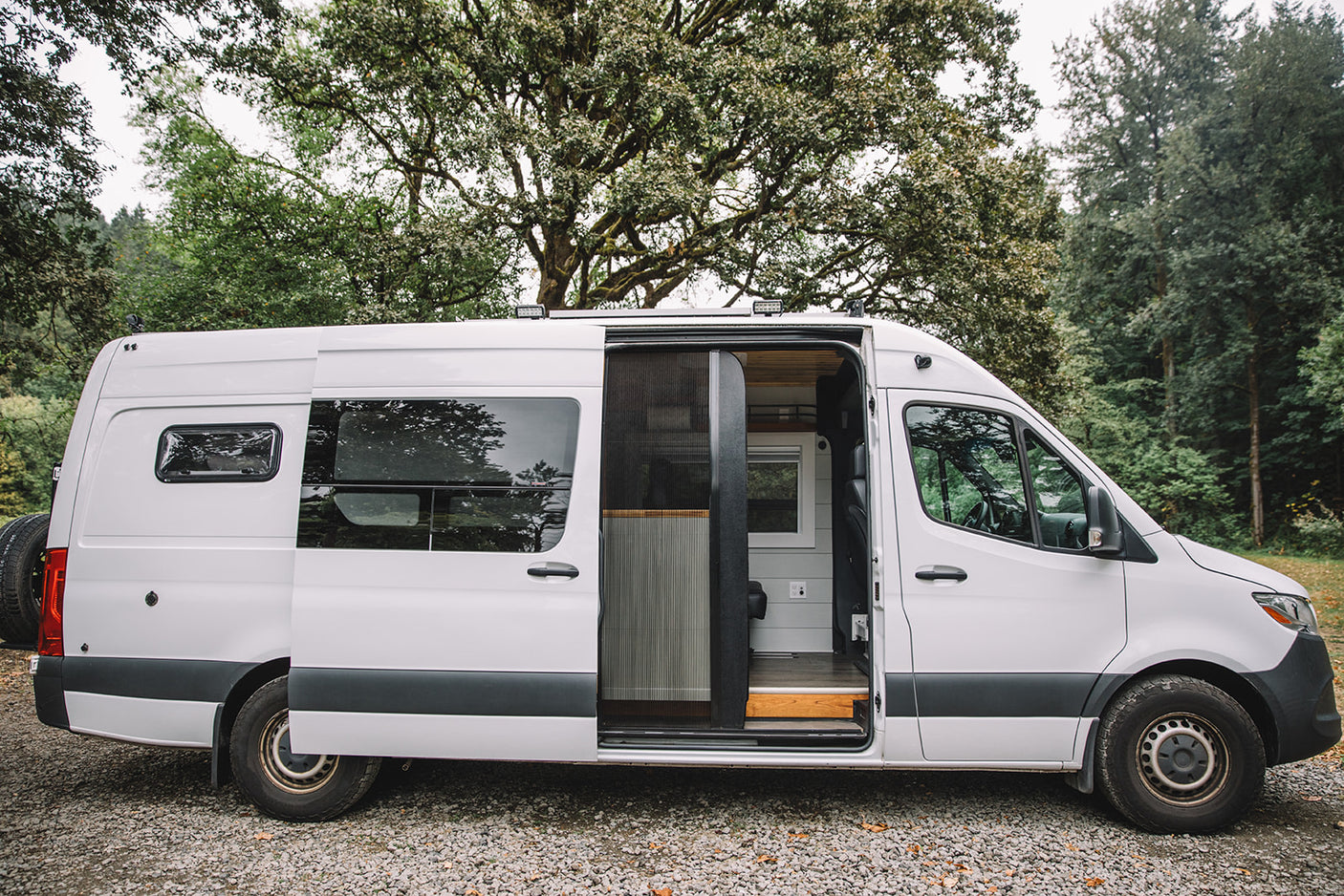 White custom camper van with open sliding door showcasing its cozy interior, perfect for an rv rental.