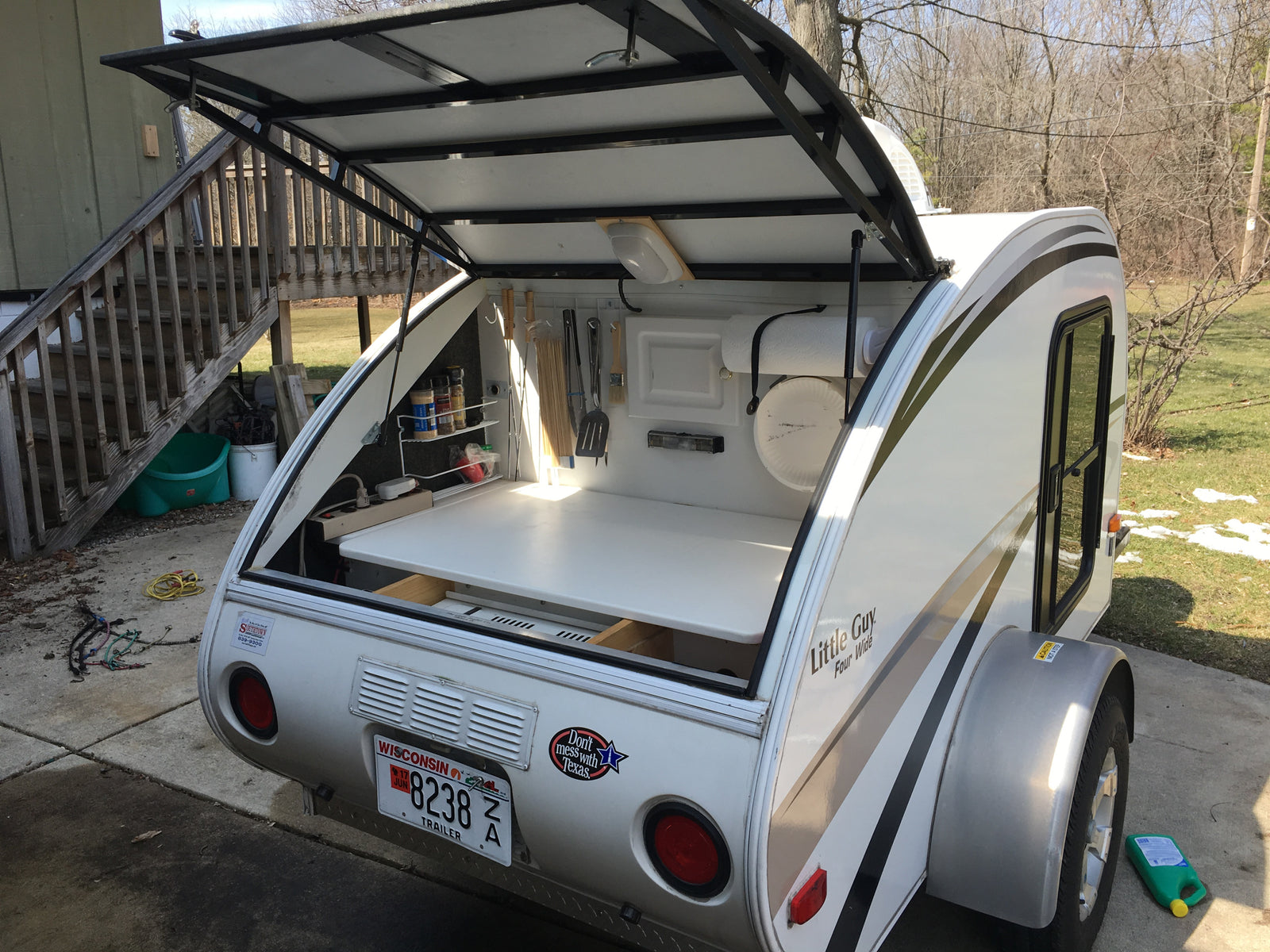 This small camper, possibly an RV rental, features an open rear galley kitchen, ideal for outdoor cooking.
