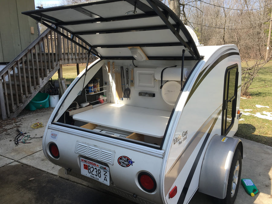 This small camper, possibly an RV rental, features an open rear galley kitchen, ideal for outdoor cooking.