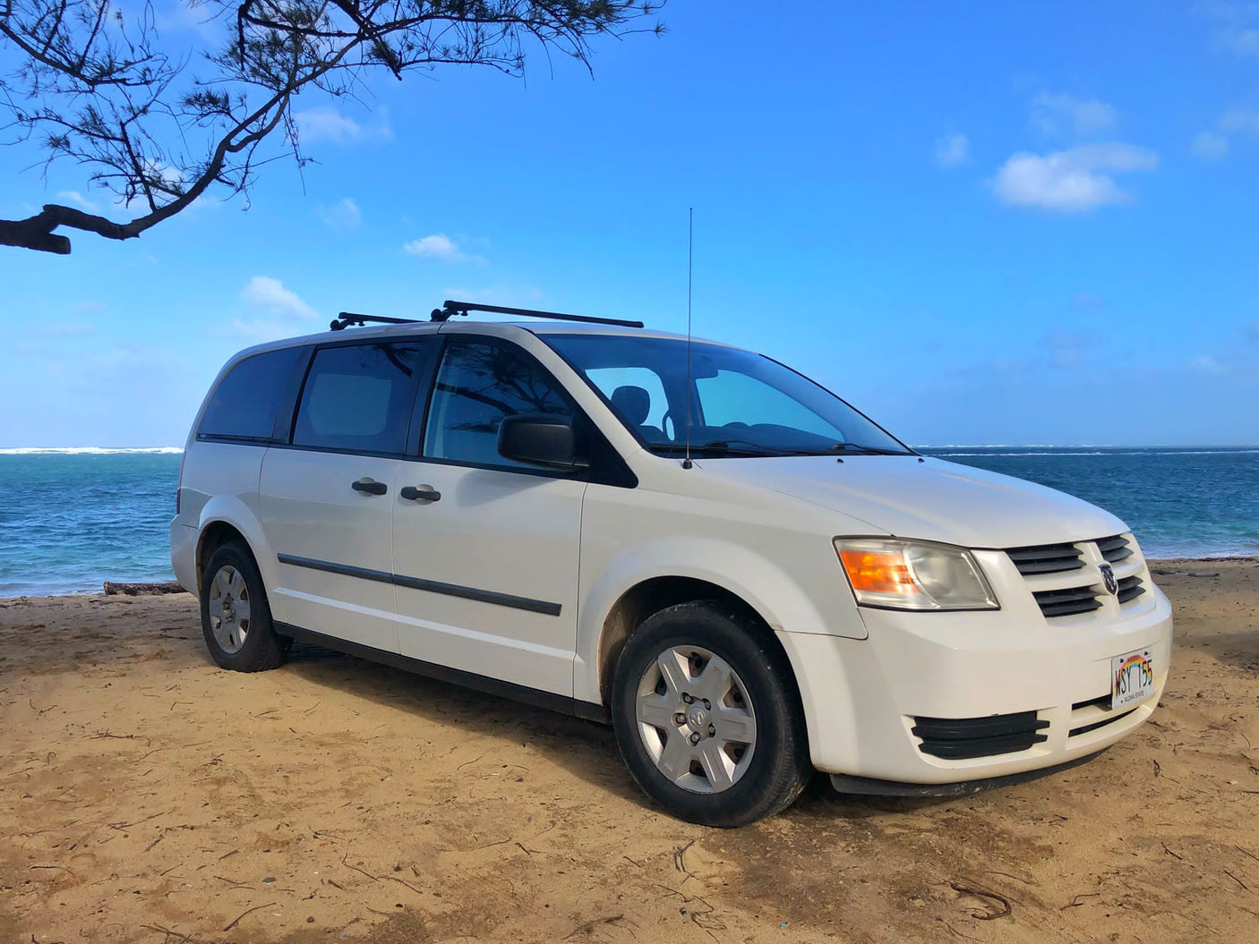 Minivan (RV rental) on a sunny Hawaii beach by the ocean, ready for island adventures.