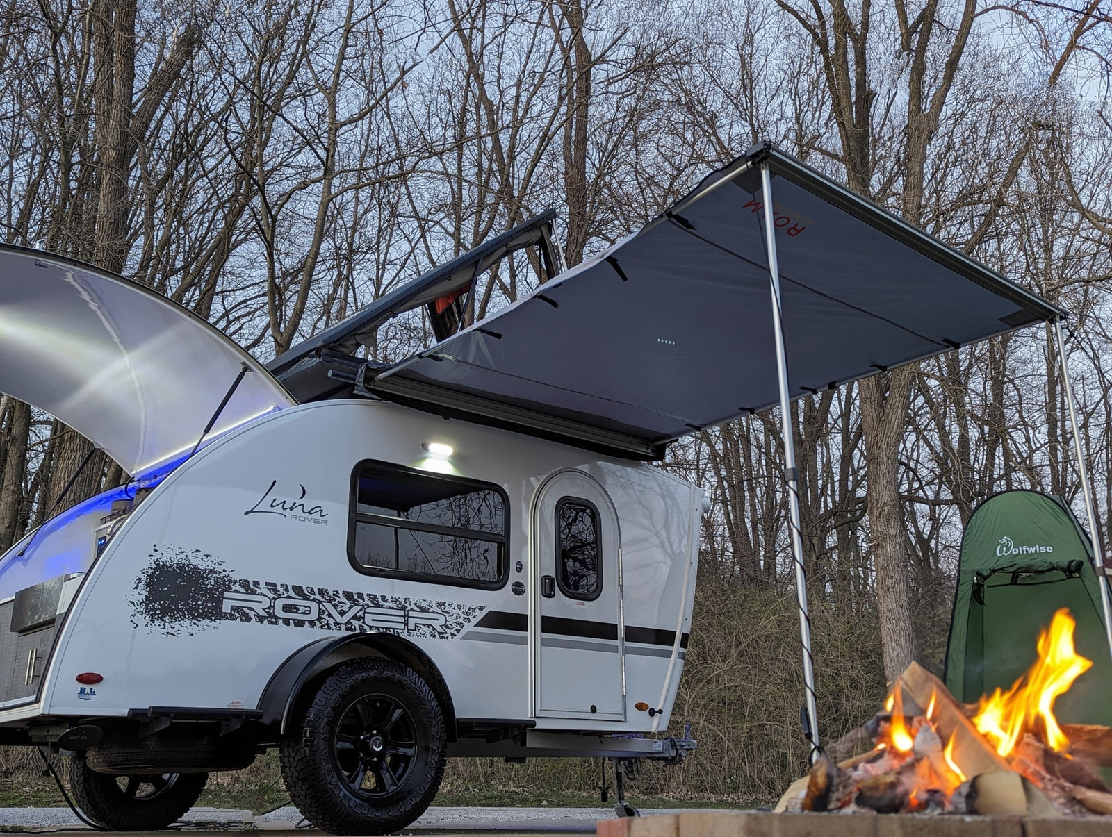 Enjoy your outdoor adventure! This Luna Rover RV rental offers a cozy setup with an extended awning and warm campfire.
