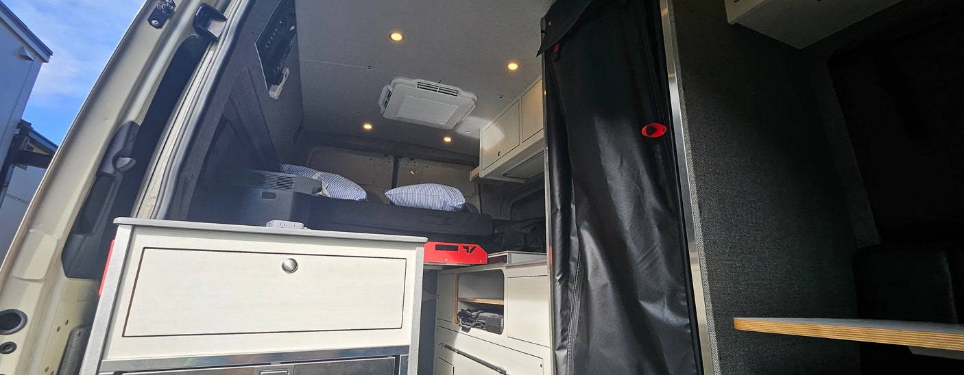 Inside this RV rental: a comfy bed, overhead AC unit, and kitchen storage, perfect for your next road trip.