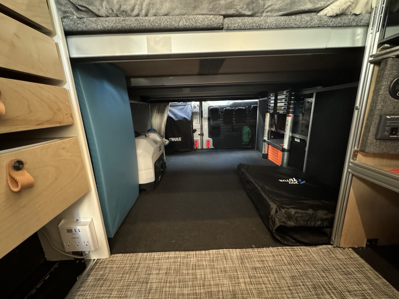 RV rental's under-bed storage organized: wood drawers, power outlet, generator, Thule bag, & sleeping pad.