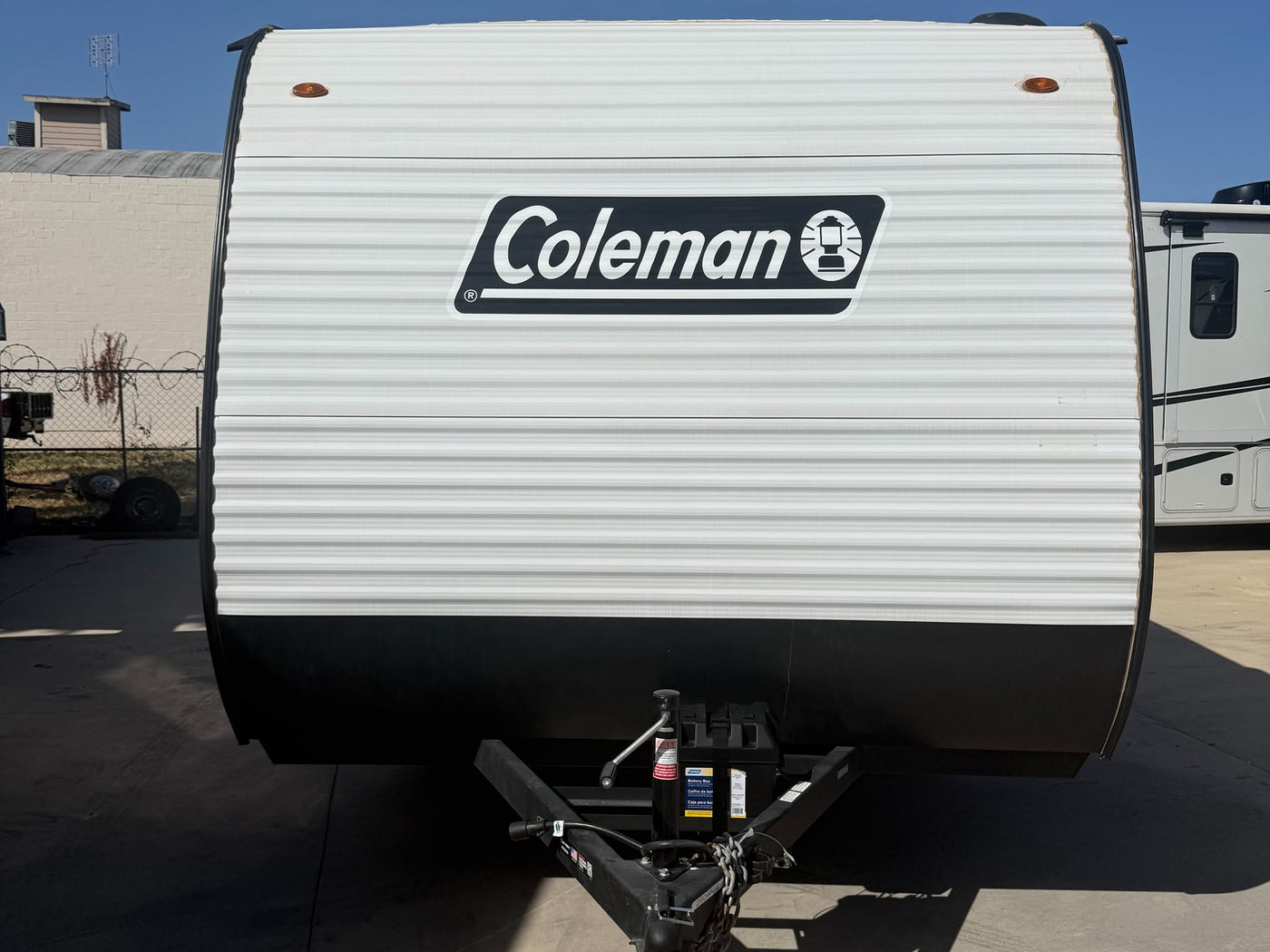 is parked on a sunny driveway.|Modern RV rental interior: kitchenette with wood-look cabinets — photo 7