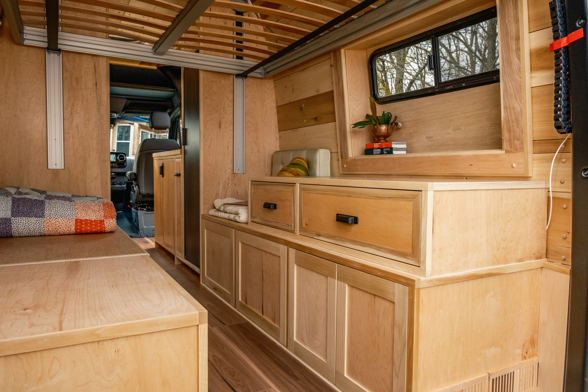 Explore this inviting RV rental with a custom light wood interior, featuring handcrafted cabinets, drawers, and a comfy bed. — photo 8