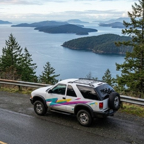 offers stunning island views from a coastal road. Consider an rv rental for similar adventures.|A white Chevy S10 Blazer RV rental with a roof-top tent & 90s graphics