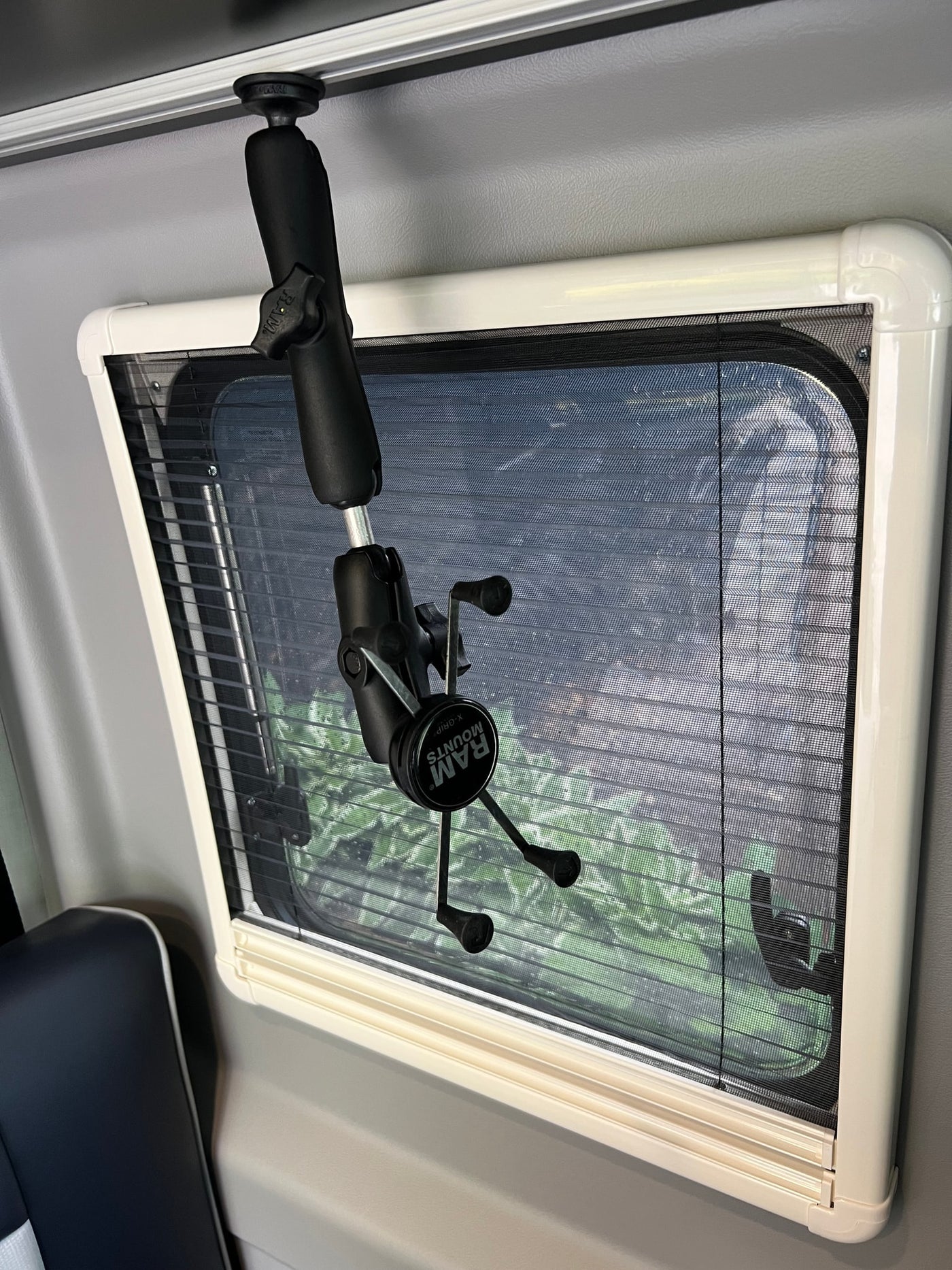 RV rental interior: window with pleated screen and a RAM Mounts phone holder attached to an overhead track. — photo 9