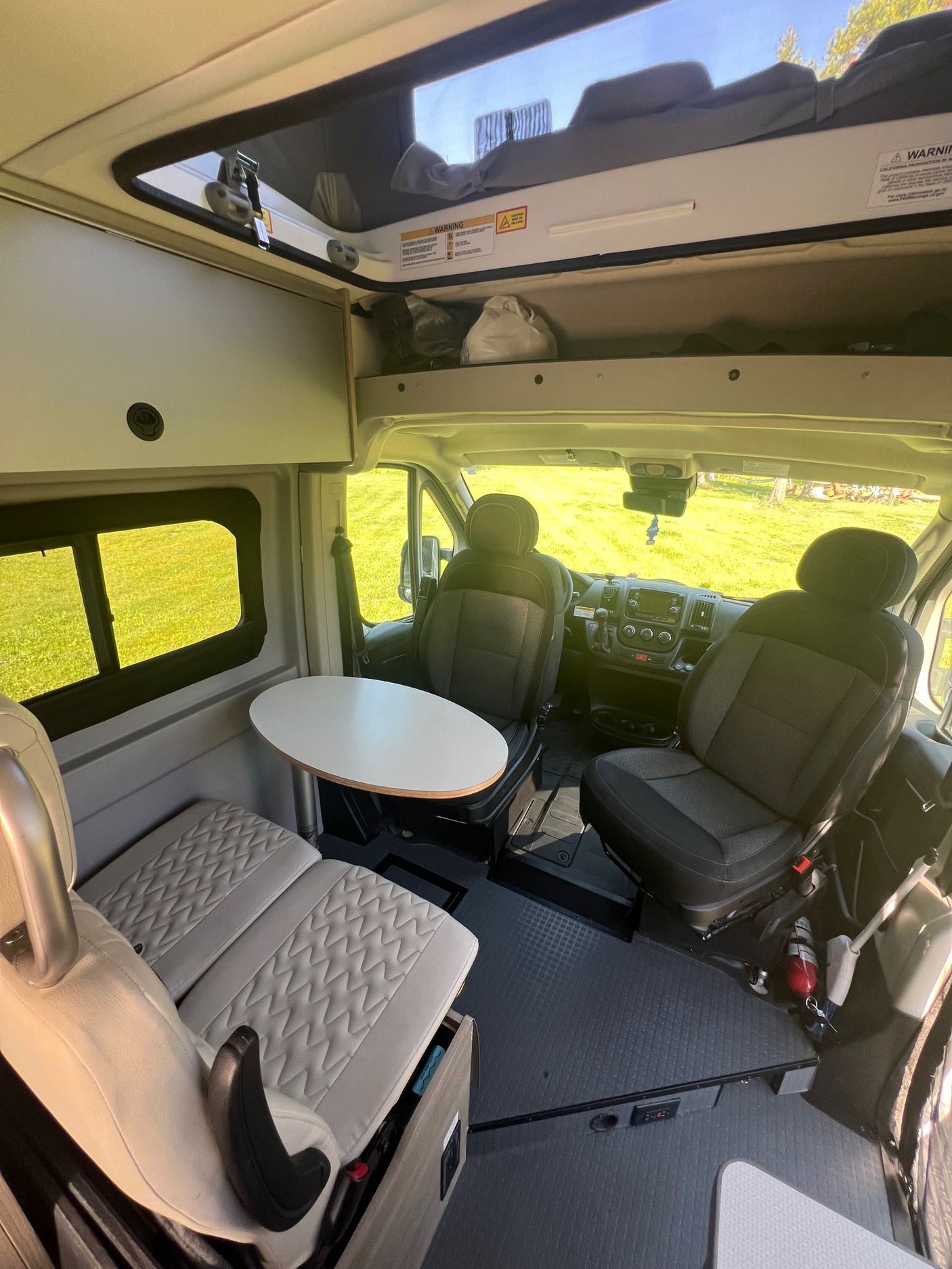Step inside this RV rental, featuring driver/passenger seats, a table, and comfortable bench seating. Ready for adventure.