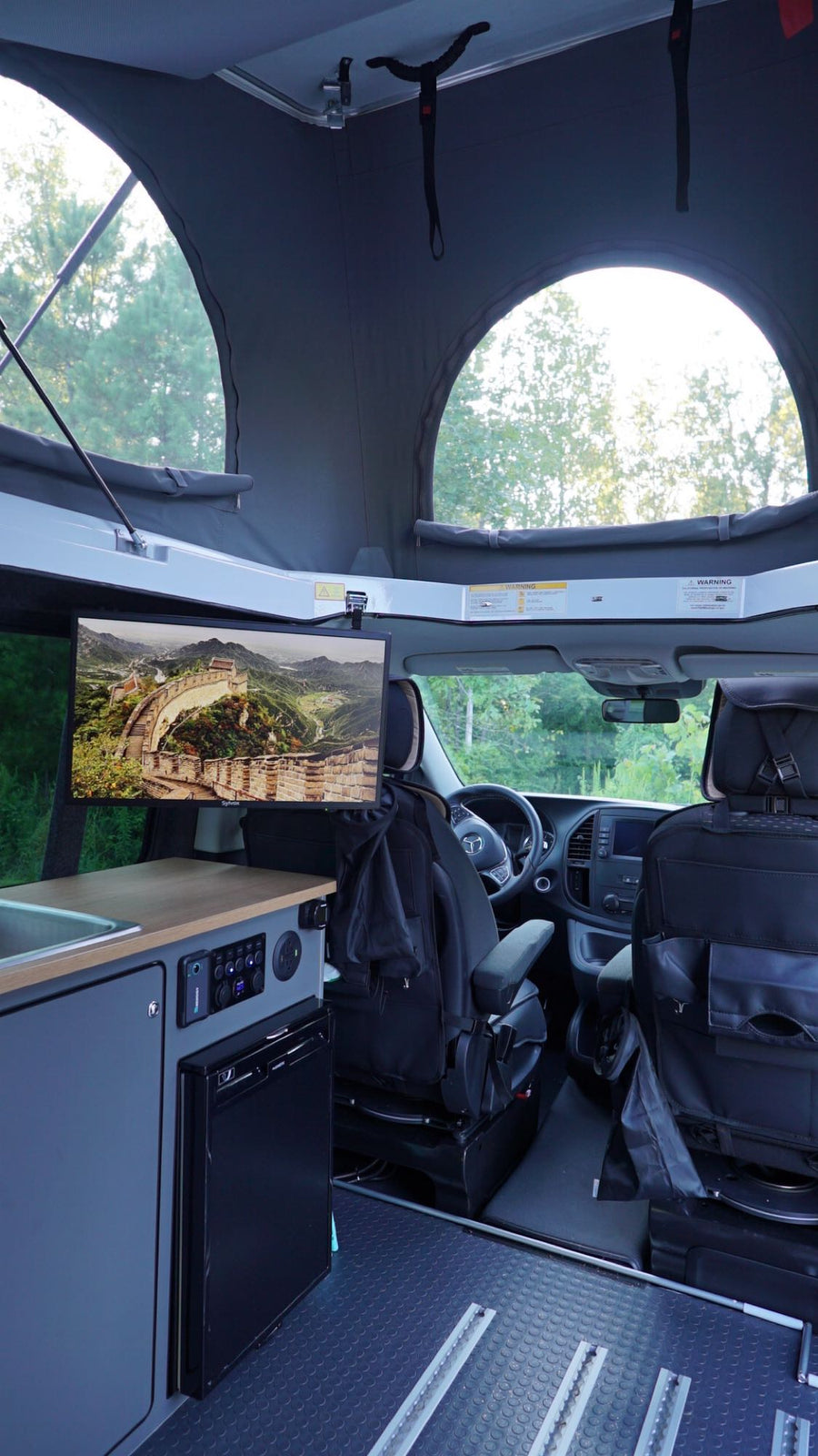 reading a book while relaxing on a comfortable bed inside an RV rental's pop-top