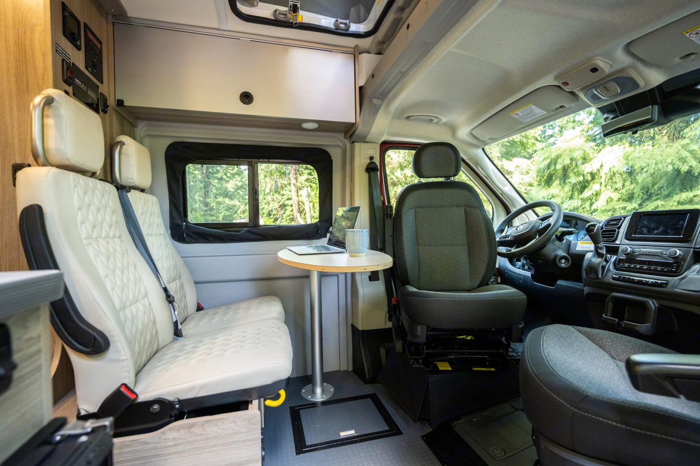 bathed in warm light from striking red rock mountains and green trees.|Interior of a modern rv rental camper van