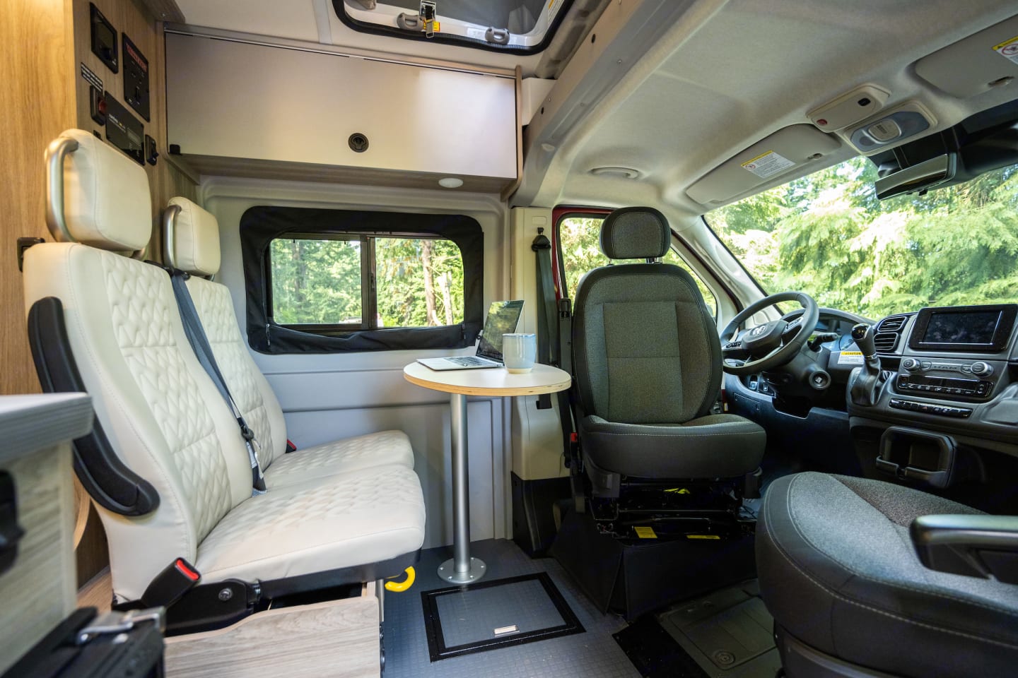 bathed in warm light from striking red rock mountains and green trees.|Interior of a modern rv rental camper van