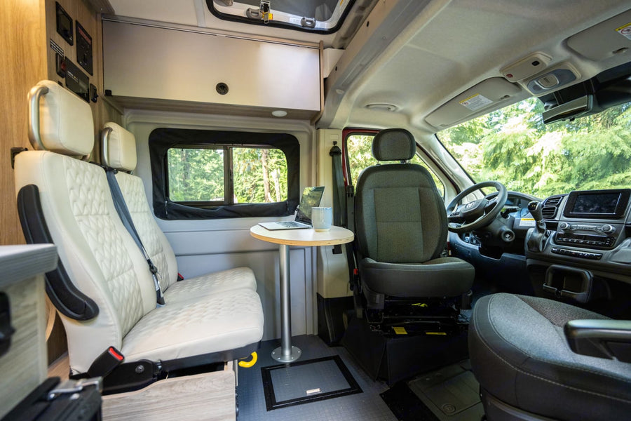 bathed in warm light from striking red rock mountains and green trees.|Interior of a modern rv rental camper van