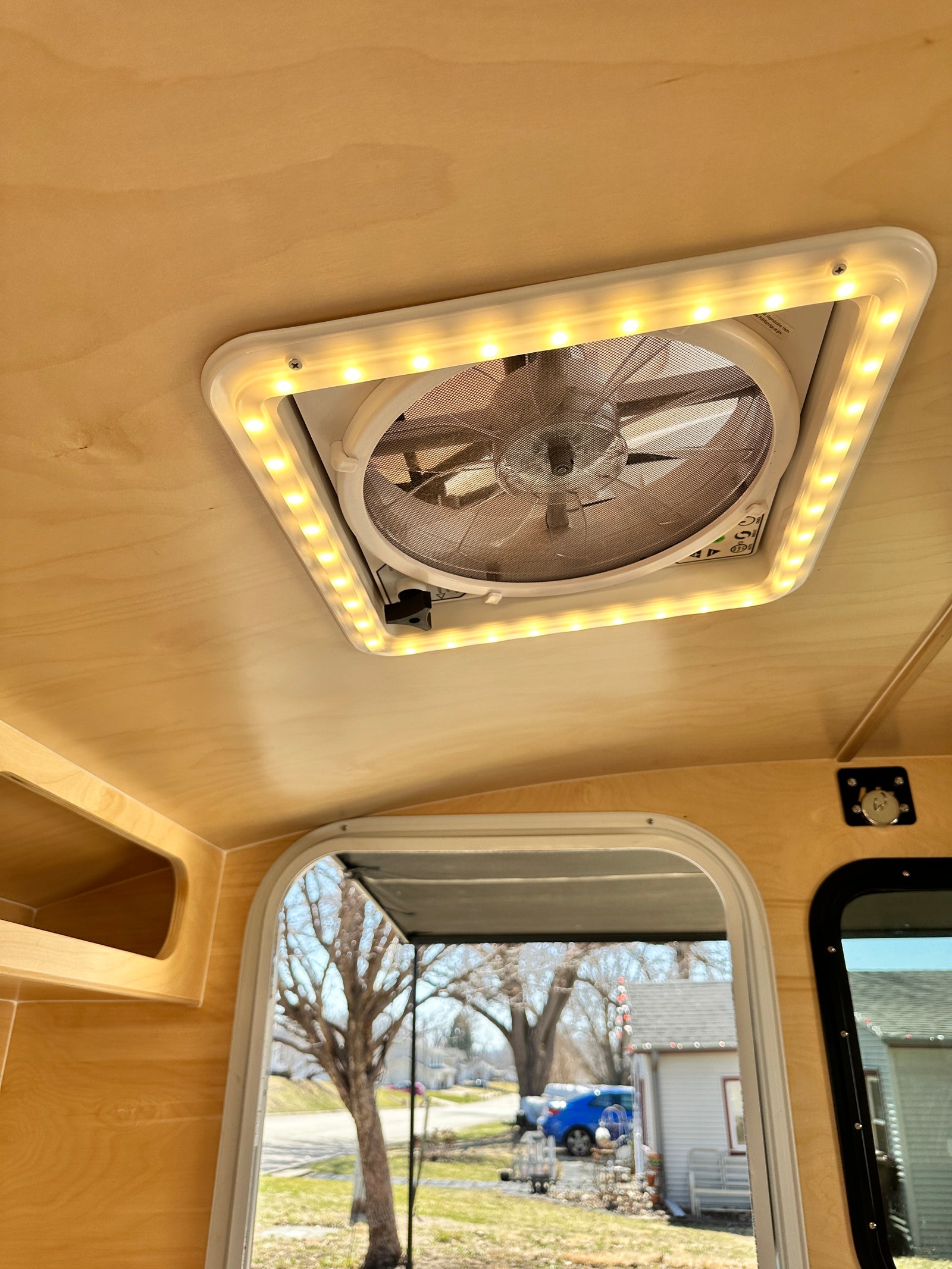 RV rental with a bright, wood-paneled interior, featuring an LED-lit ceiling fan and an outside view through the window.