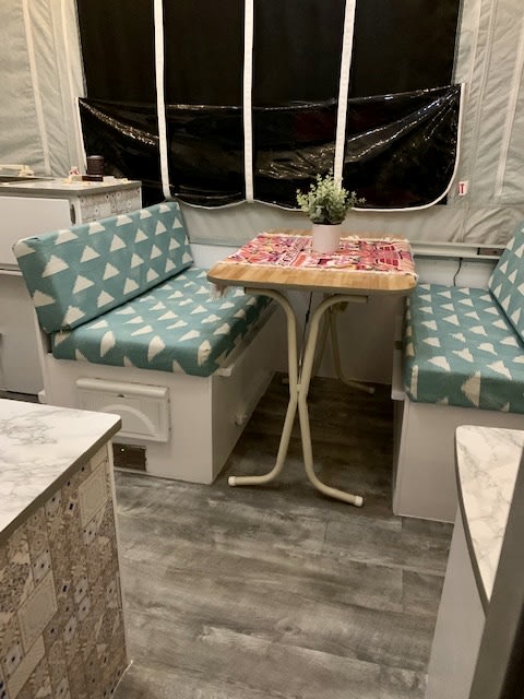 functional living space.|Interior of an RV rental pop-up camper featuring a cozy bed
