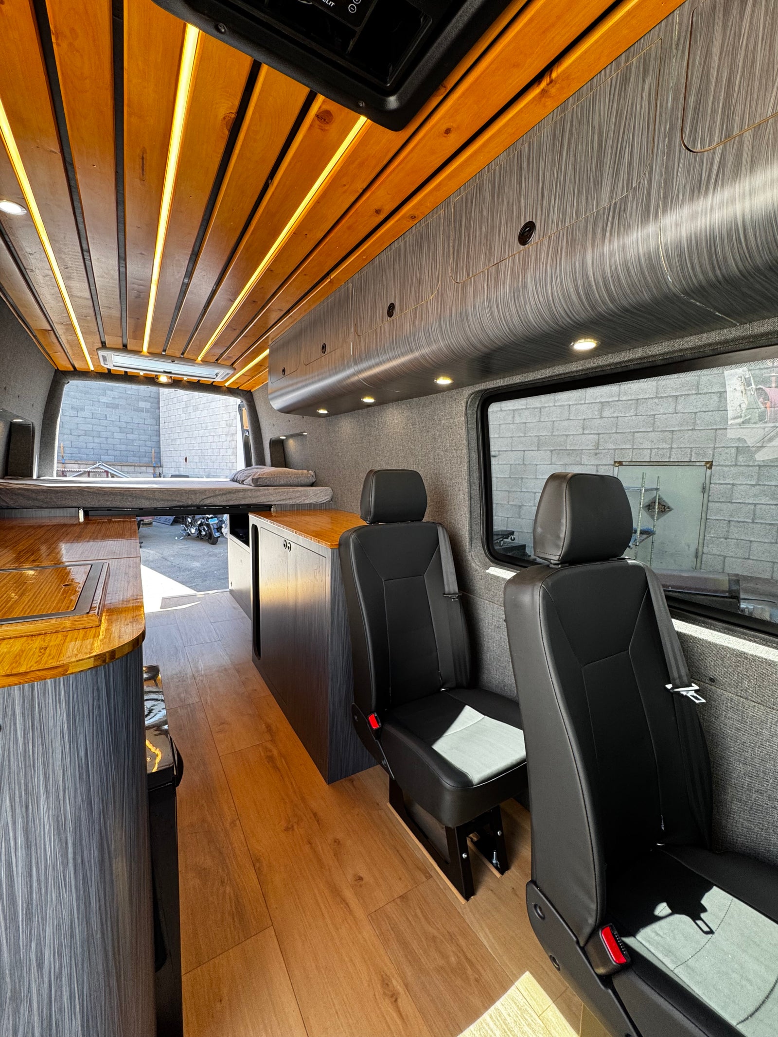 Spacious camper van interior, perfect for RV rental adventures. Enjoy the custom wooden ceiling, comfortable seating, and kitchenette.