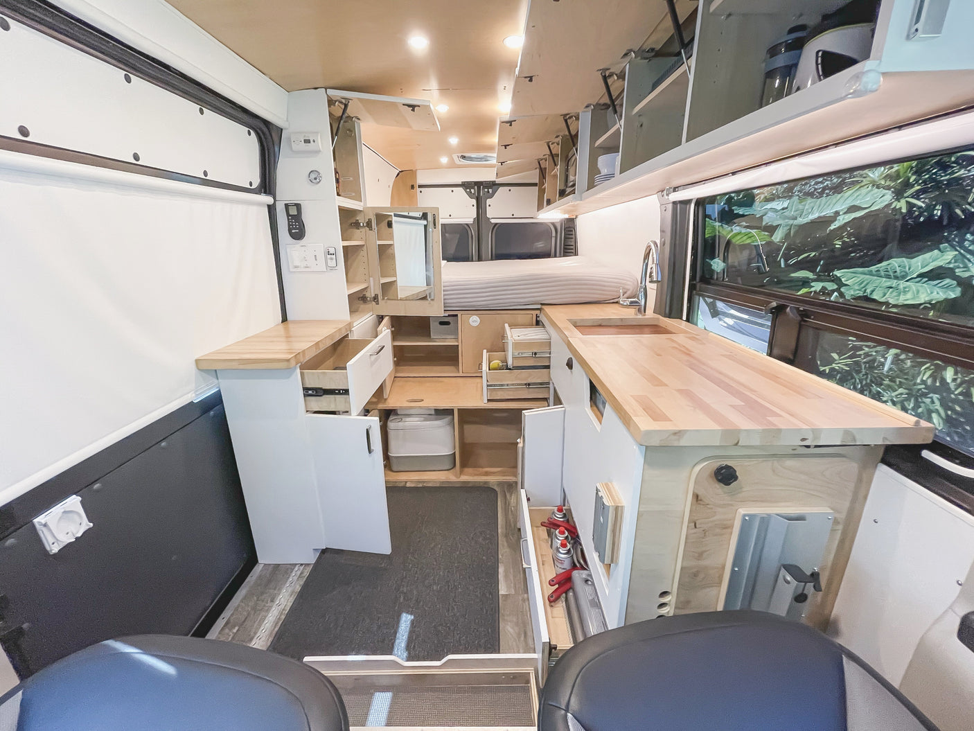 Inside a stylish RV rental: compact kitchen, cozy bed, and clever storage maximize space in this modern camper van.