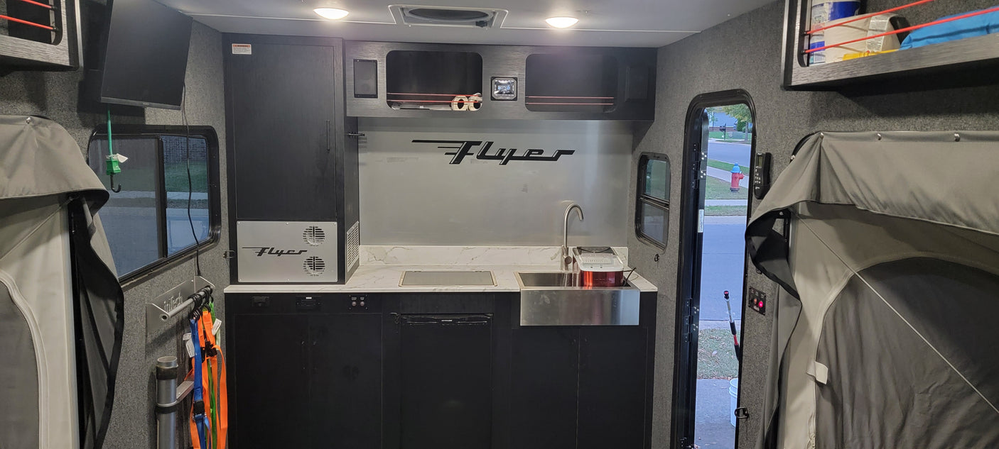 Modern rv rental interior: A compact galley with sink, stovetop, and integrated storage, perfect for your next camper adventure.