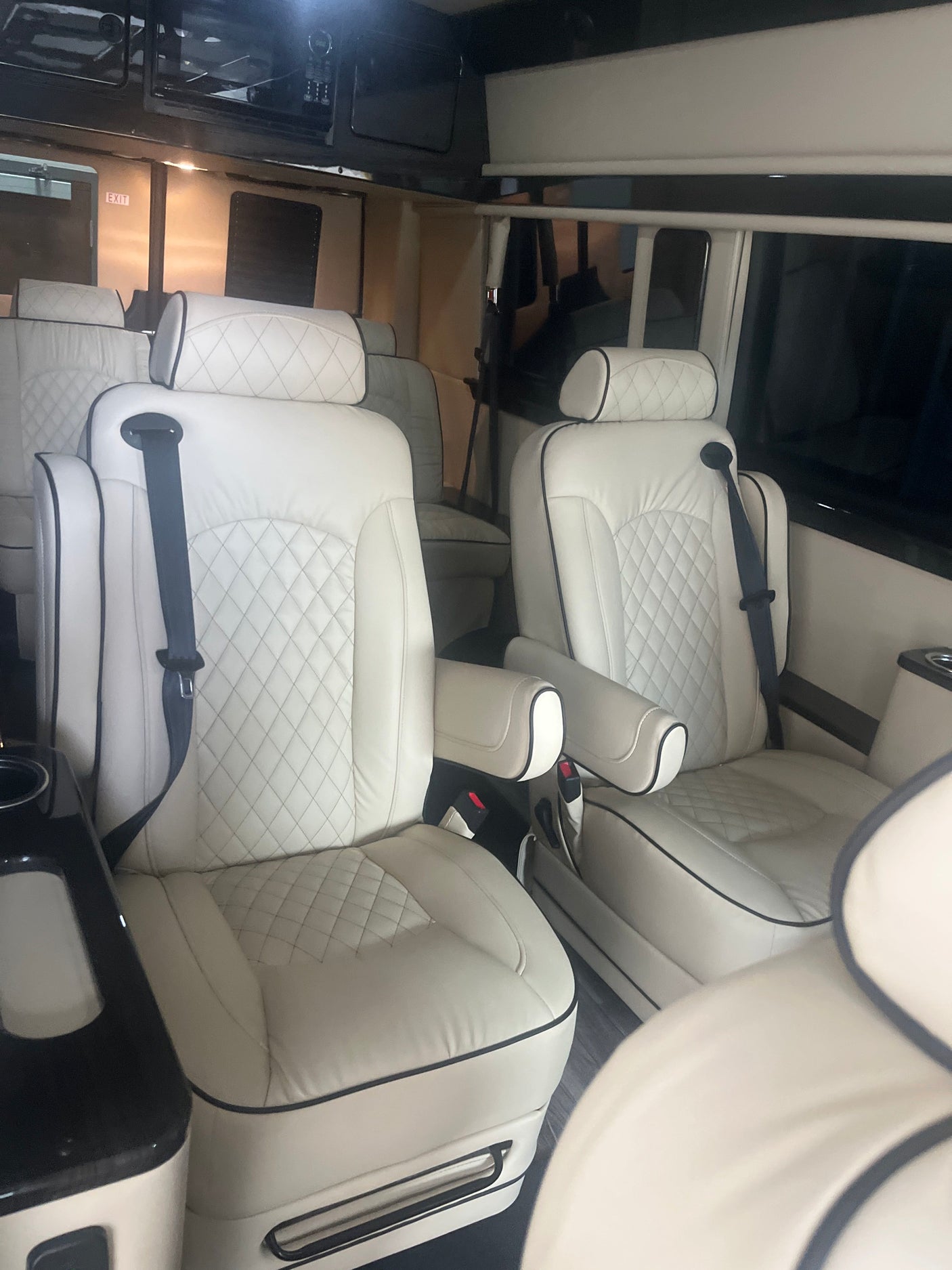 Inside an RV rental, showcasing plush white quilted leather seats with black piping & seatbelts. A spacious, luxury interior.