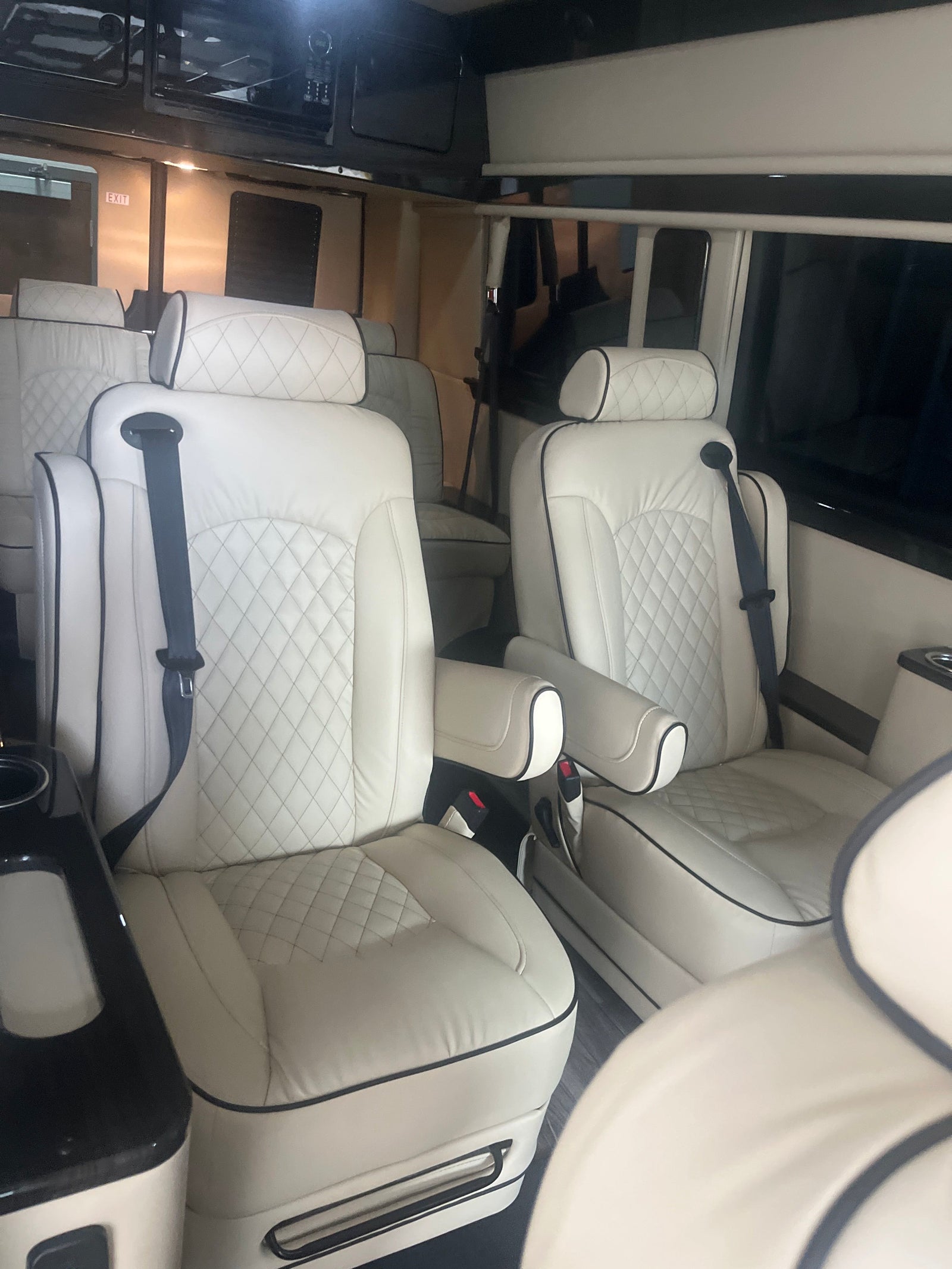 Inside an RV rental, showcasing plush white quilted leather seats with black piping & seatbelts. A spacious, luxury interior.