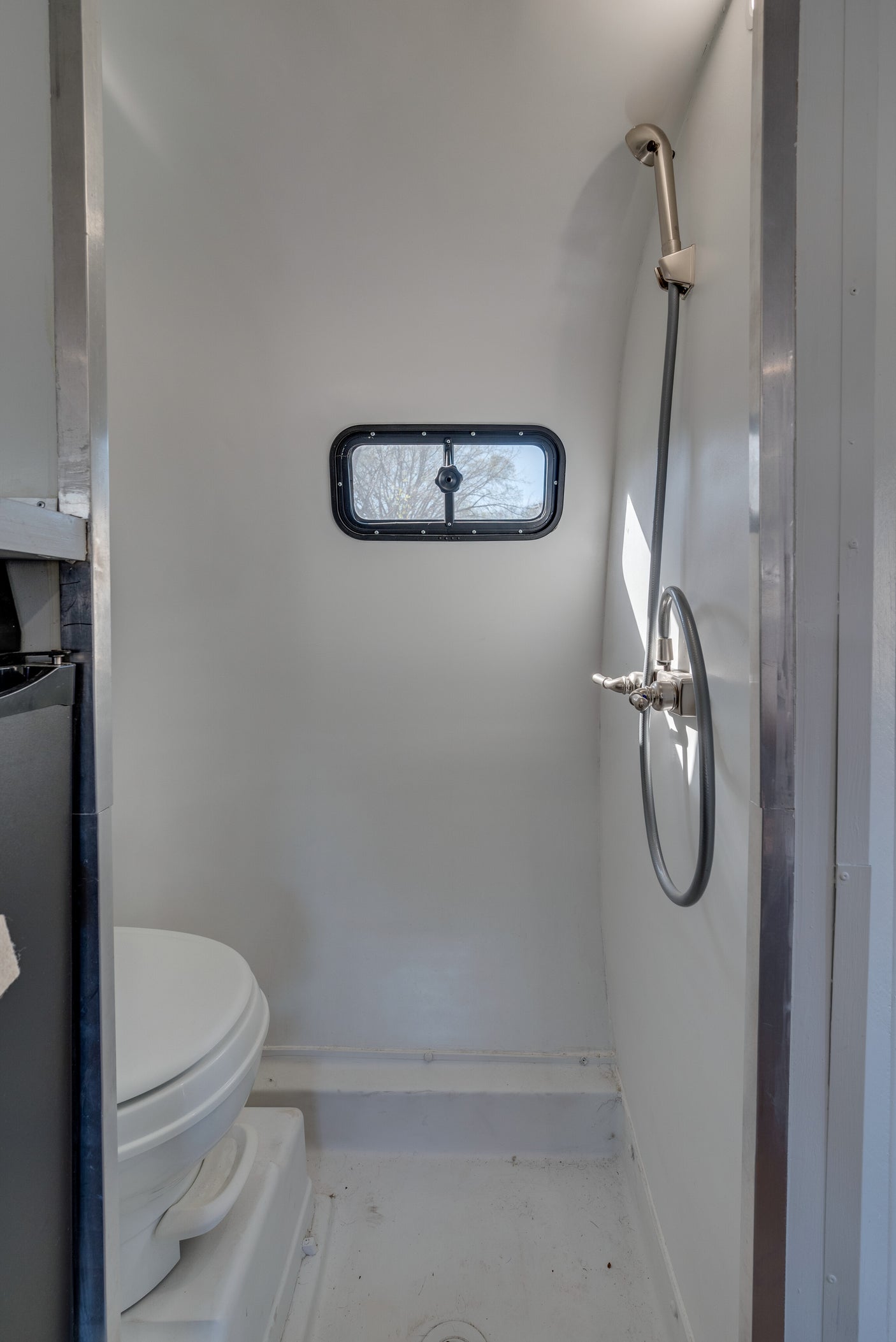 Clean, compact RV rental bathroom with shower, toilet, and window, perfect for road adventures.