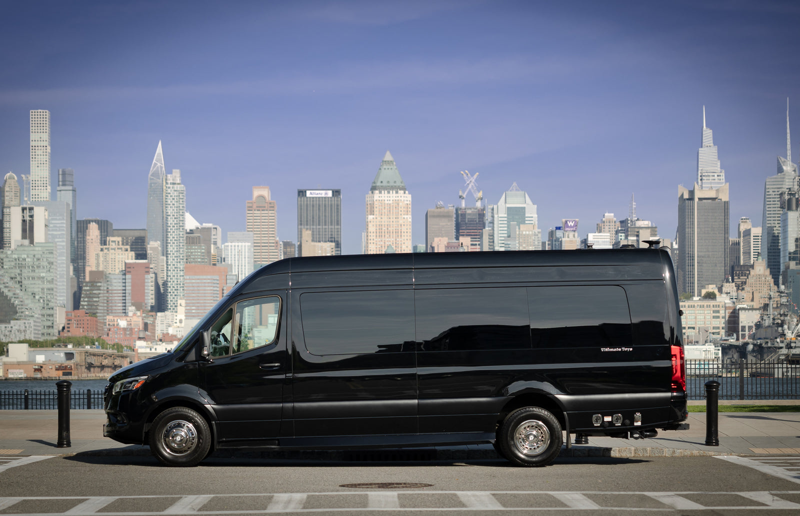 parked before a stunning city skyline.|Sleek black Mercedes-Benz Sprinter RV rental parked with a vibrant NYC skyline background. Ideal for luxury travel.|Cream-colored