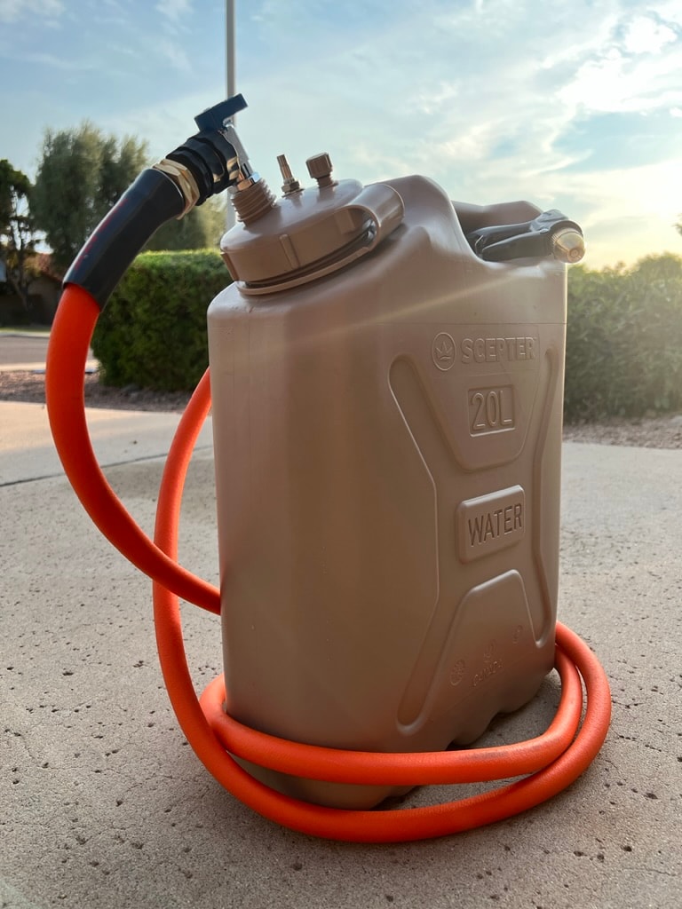 A tan Scepter 20L water can with an orange hose provides portable water for RV rental trips or camping adventures. — photo 17