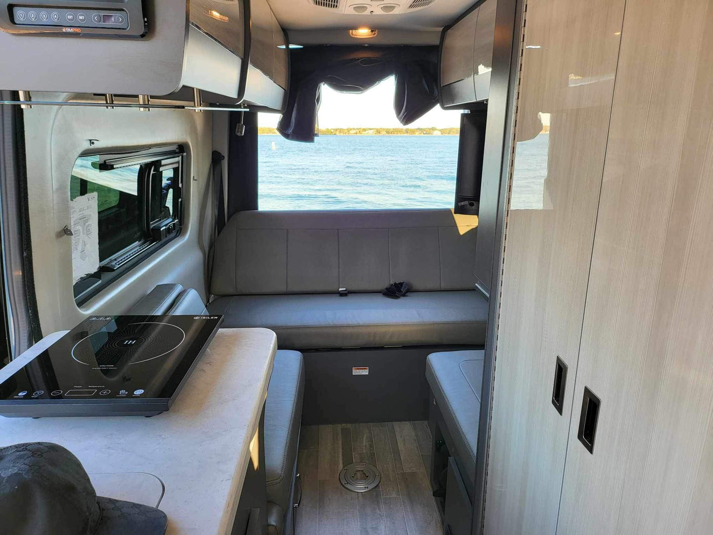 RV rental interior: cozy camper with kitchen, seating, and stunning lake view for your next adventure.