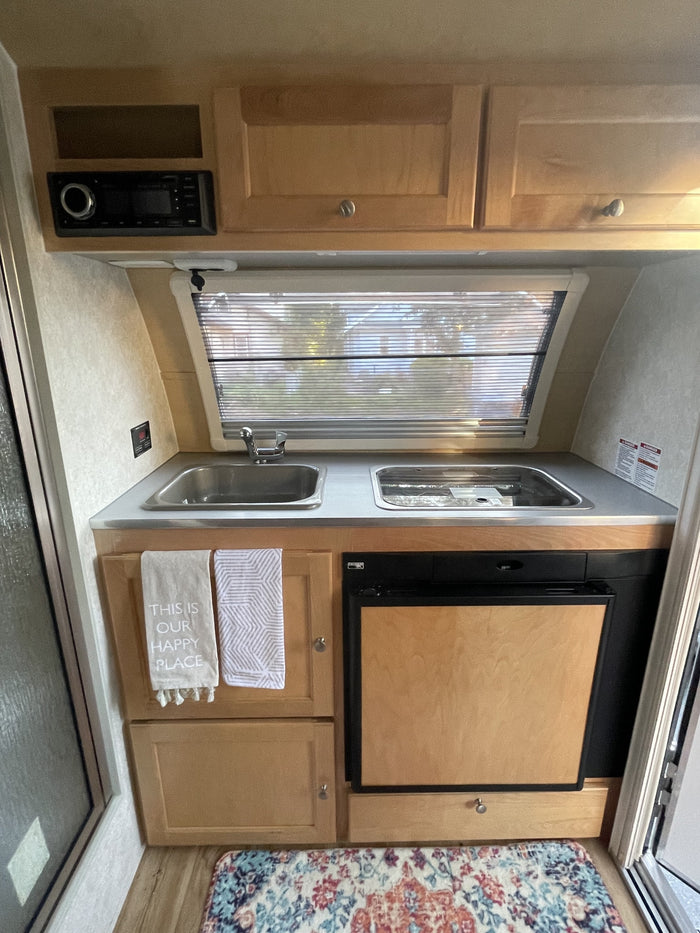perfect for an RV rental experience. This compact travel trailer features a window and round door.|Inside an RV rental: a functional interior with a cozy dinette