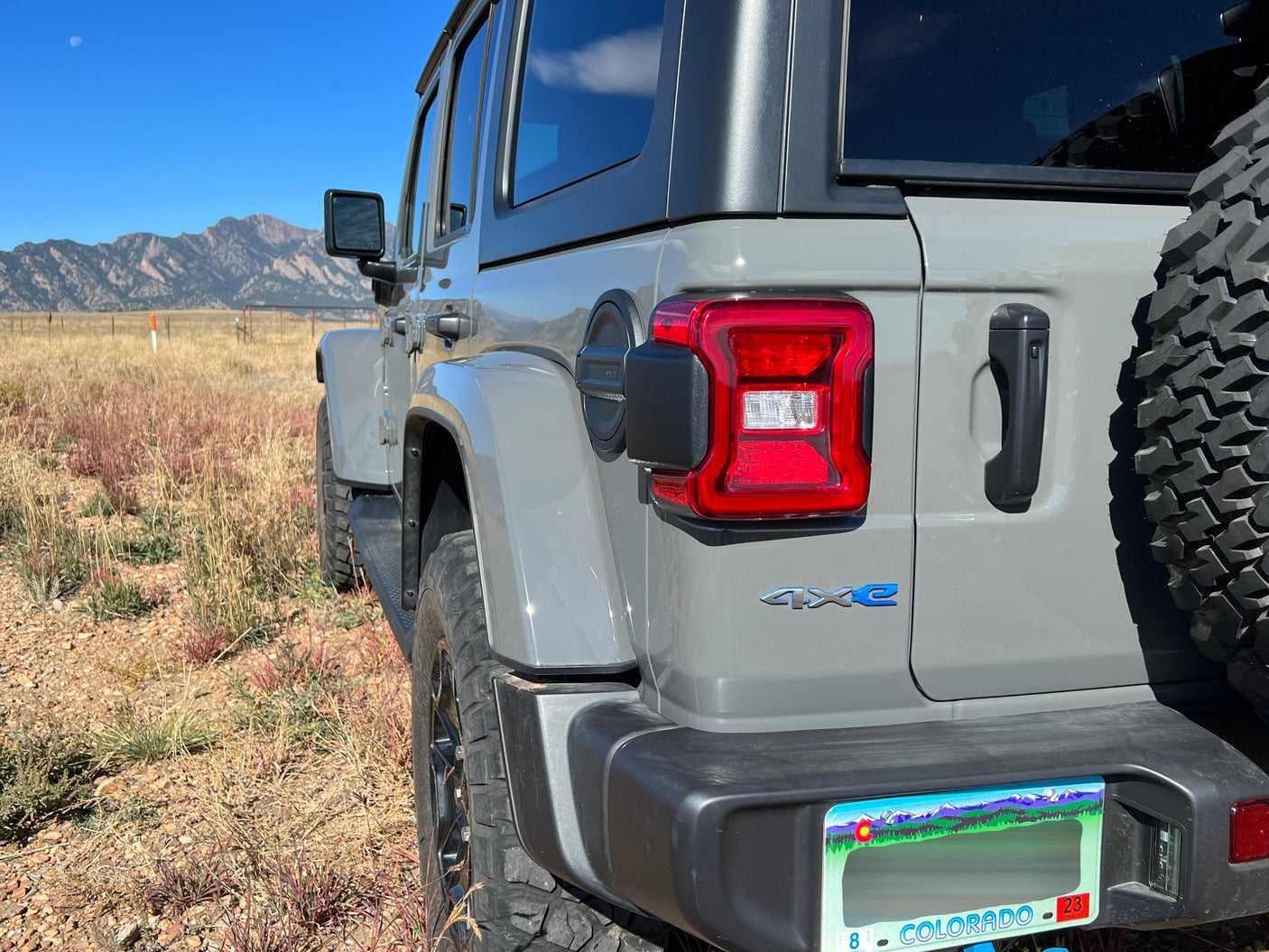 Gray Jeep Wrangler 4xe in Colorado's outdoors with mountains & moon. Perfect for adventure, just like an RV rental journey.
