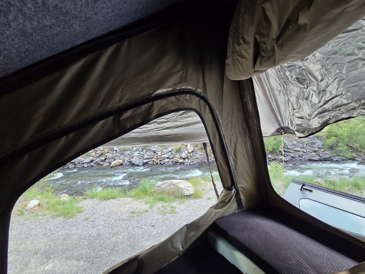 Inside an RV rental rooftop tent, a comfy sleeping area overlooks a scenic river view. Perfect for outdoor adventure. — photo 7