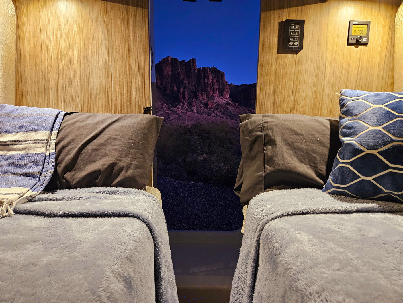 Cozy RV rental interior with two beds facing a stunning twilight mountain view, perfect for comfortable travels.