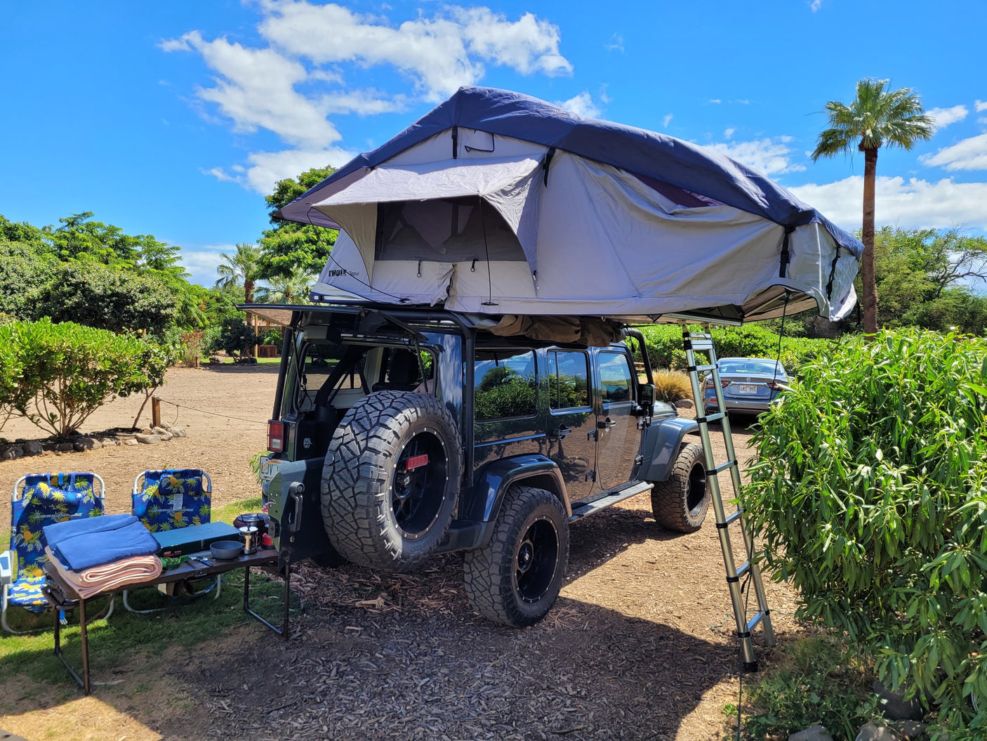 Adventure awaits! This rv rental Jeep Wrangler features a deployed rooftop tent and full camp setup, perfect for outdoor escapes.