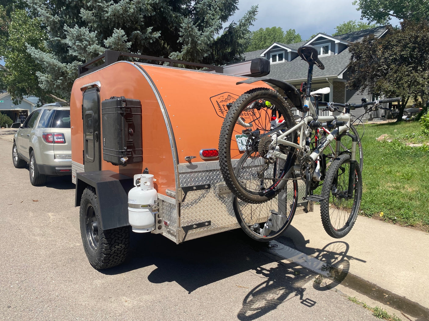 Orange teardrop RV rental with mountain bikes for outdoor adventures. Perfect for camping trips.