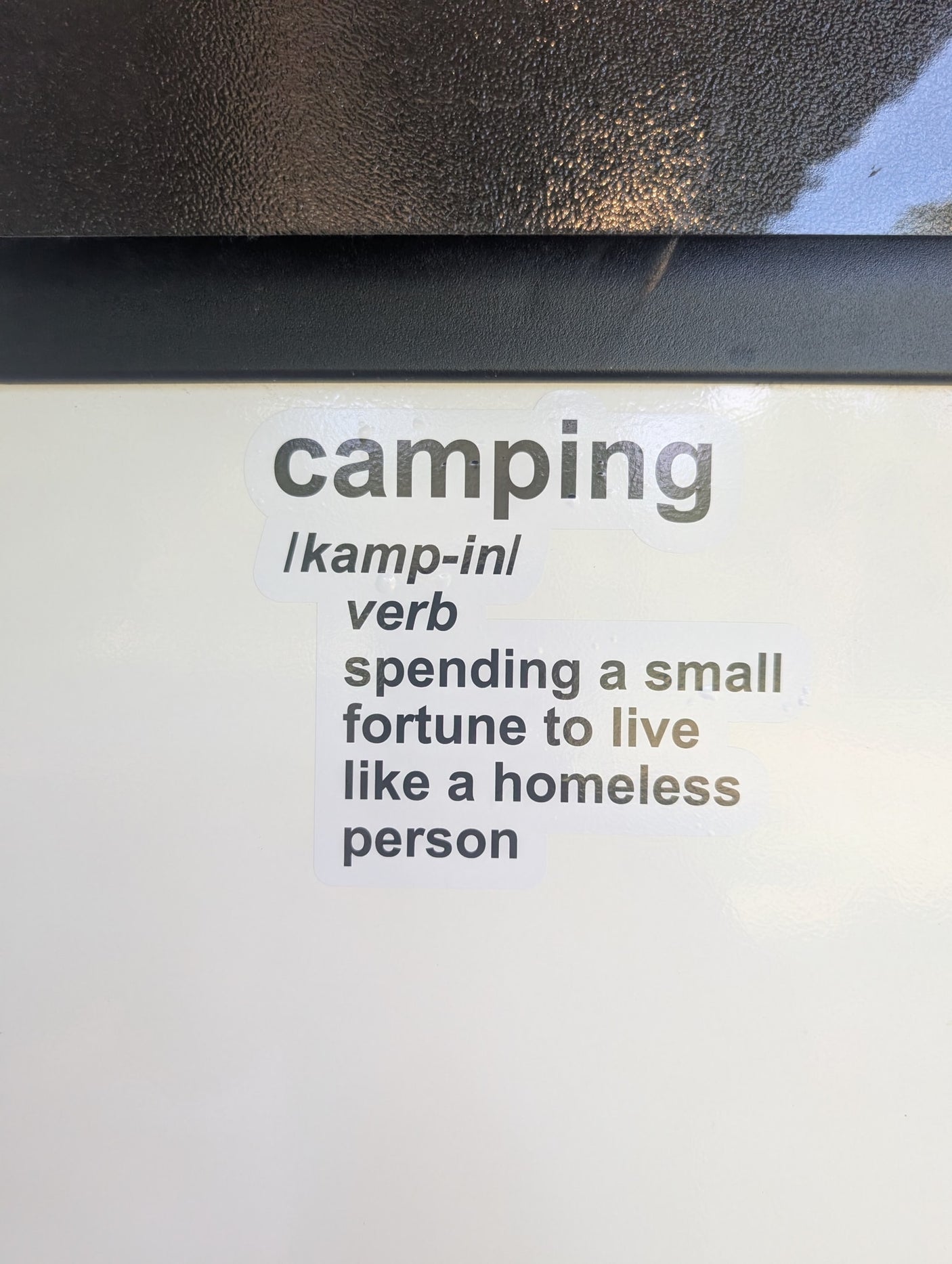 A humorous sticker defines "camping": "spending a small fortune to live like a homeless person." A pricey RV rental relates!