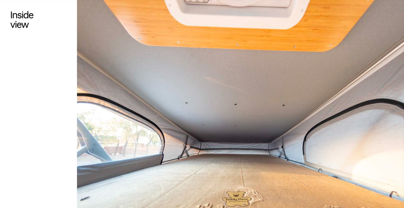 RV rental interior: spacious pop-top sleeping area with bed, large windows, and natural light.