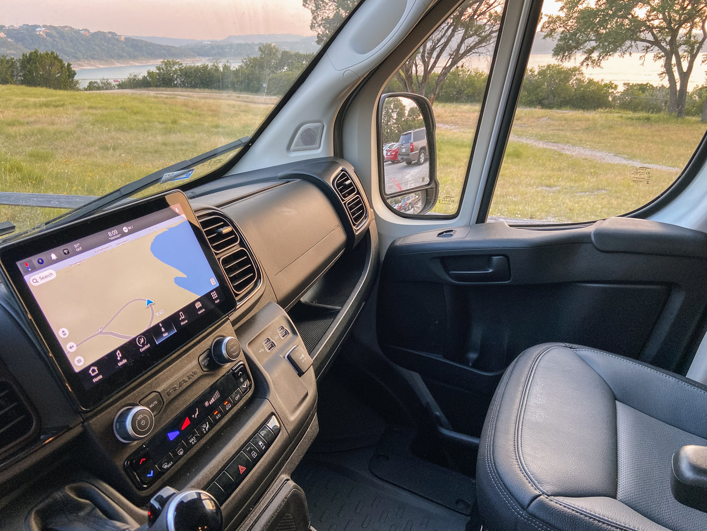 Scenic view from an RV rental's dashboard, featuring a navigation screen showing "Coe Rd" and a lake. Perfect nature stop.