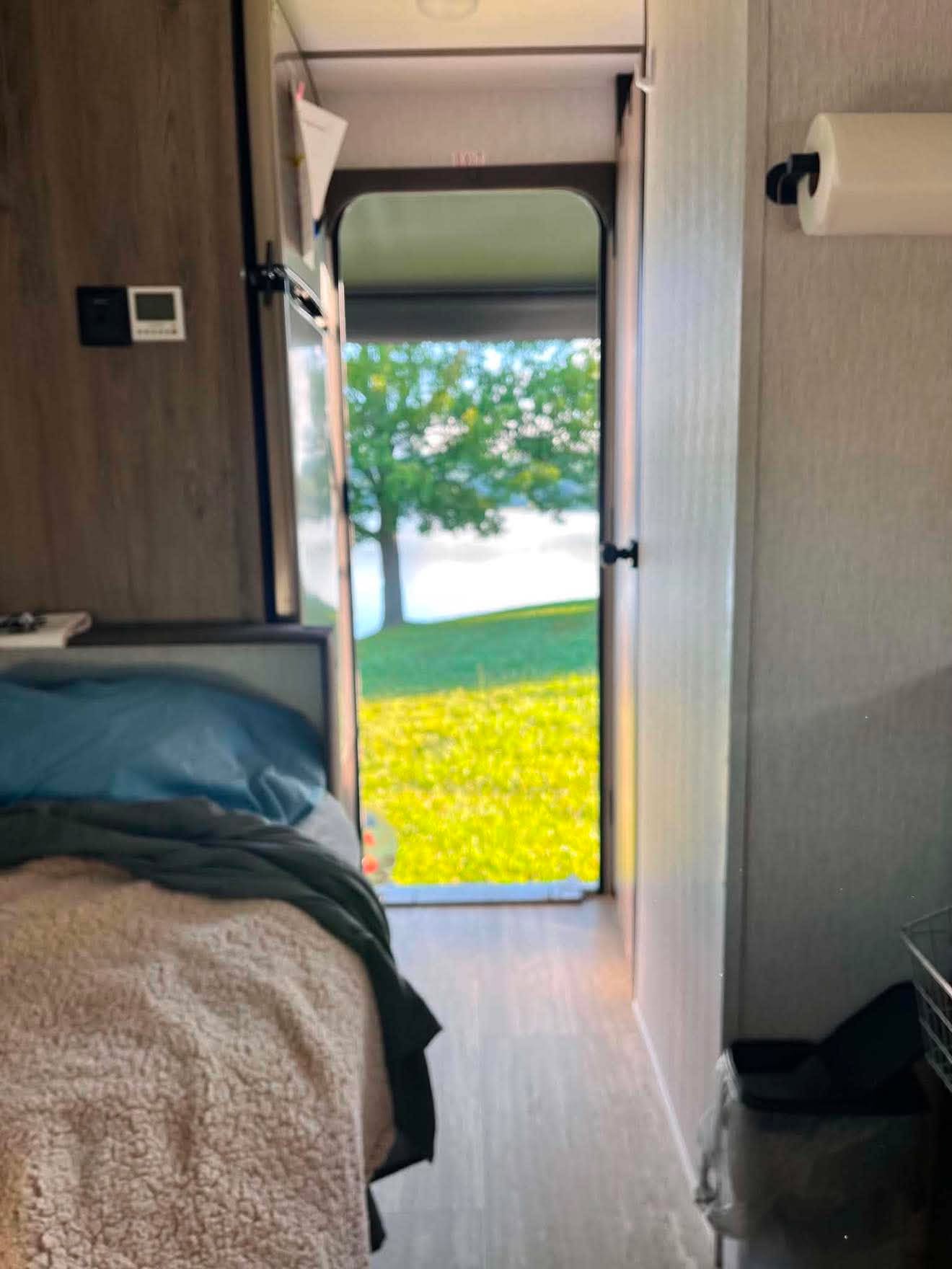 and mirrored cabinet.|RV rental interior showcasing a comfortable main bed — photo 8